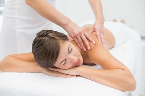 Close up of an attractive young woman receiving shoulder massage at spa center